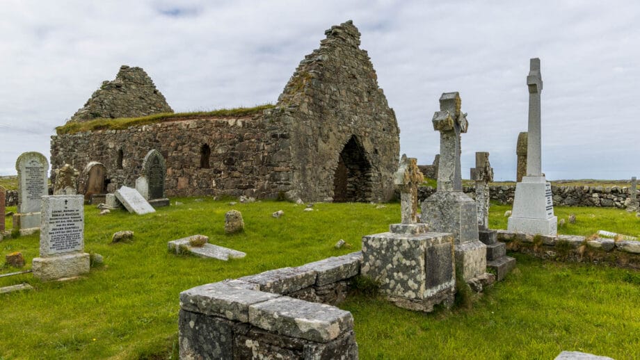 Eine Kirchenruine umgeben von einem Friedhof.