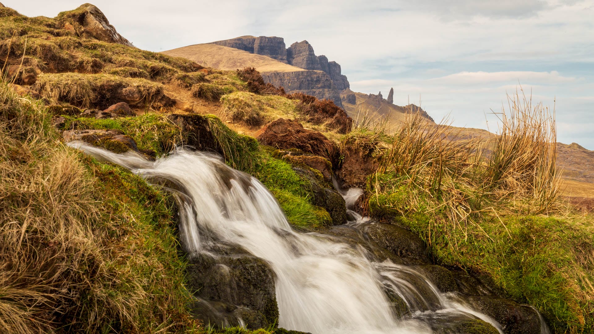 Der Wasserfall Bride’s Veil mit der Felsnadel des Old Man of Storr dahinter auf der Isle of Skye